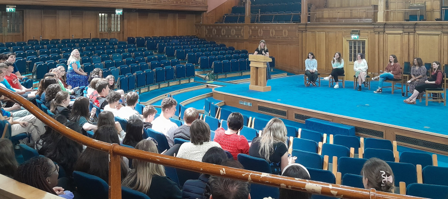Colour photos of school pupils and teachers sat in the Assembly Hall watching the student panel from the 2023 Discovery Day